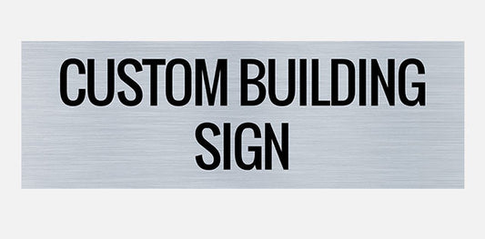 A rectangular metal building sign with the text 'CUSTOM BUILDING SIGN' in bold capital letters.