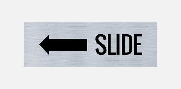 A metal door sign with the text 'SLIDE' printed in bold black letters, indicating a directional instruction to slide left.