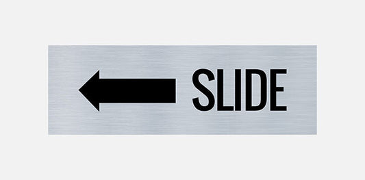 A metal door sign with the text 'SLIDE' printed in bold black letters, indicating a directional instruction to slide left.